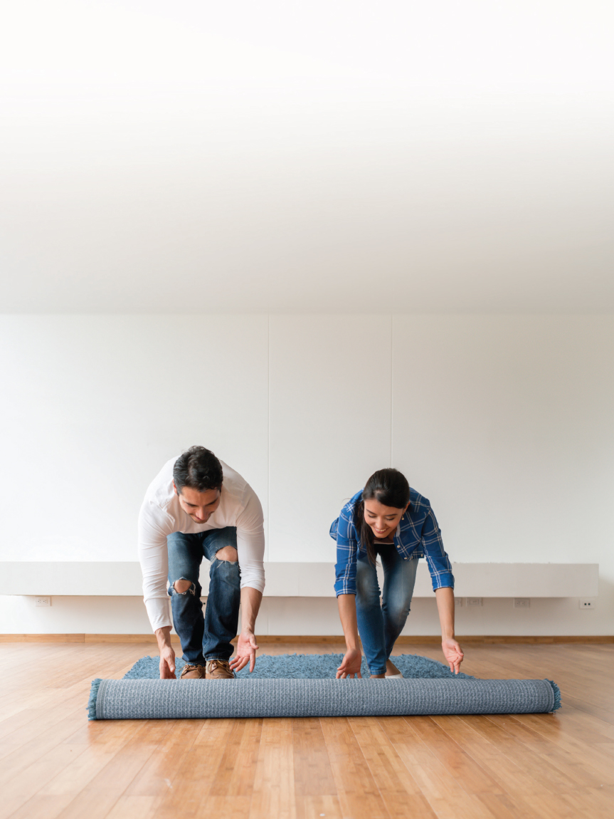 Couple Rolling out an Area Rug over Hardwood Floor